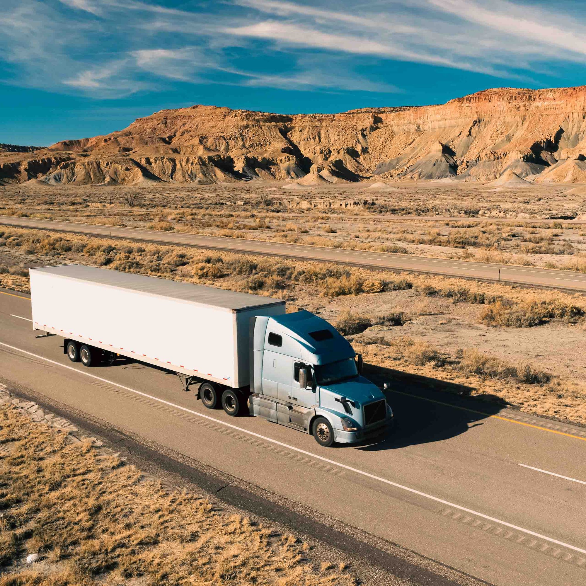 semi truck driving across a long road